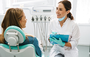 Dentist smiling at patient while taking notes on clipboard