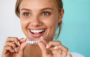 Woman smiling while holding teeth whitening tray