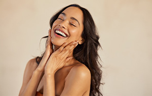 Woman with beautiful teeth smiling against beige background