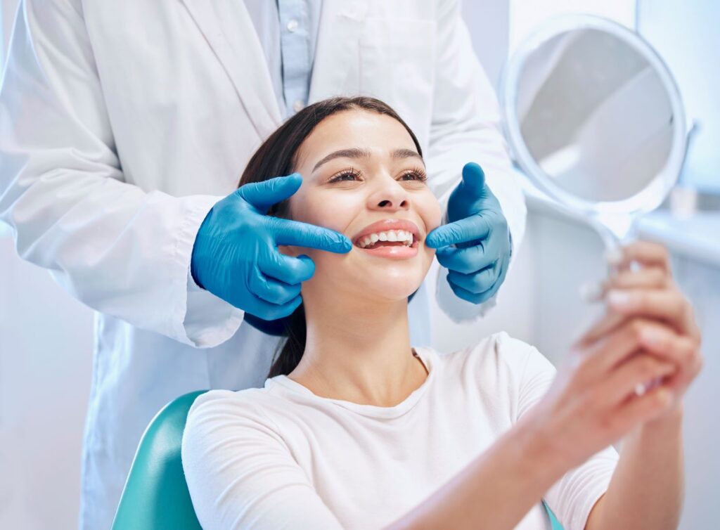 A woman at the dentist looking in the mirror at her smile.